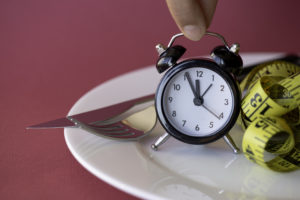 intermittent-fasting-clock-over-a-food-plate