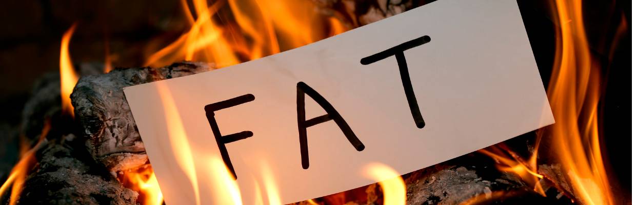 The word fat written on a piece of paper being burned